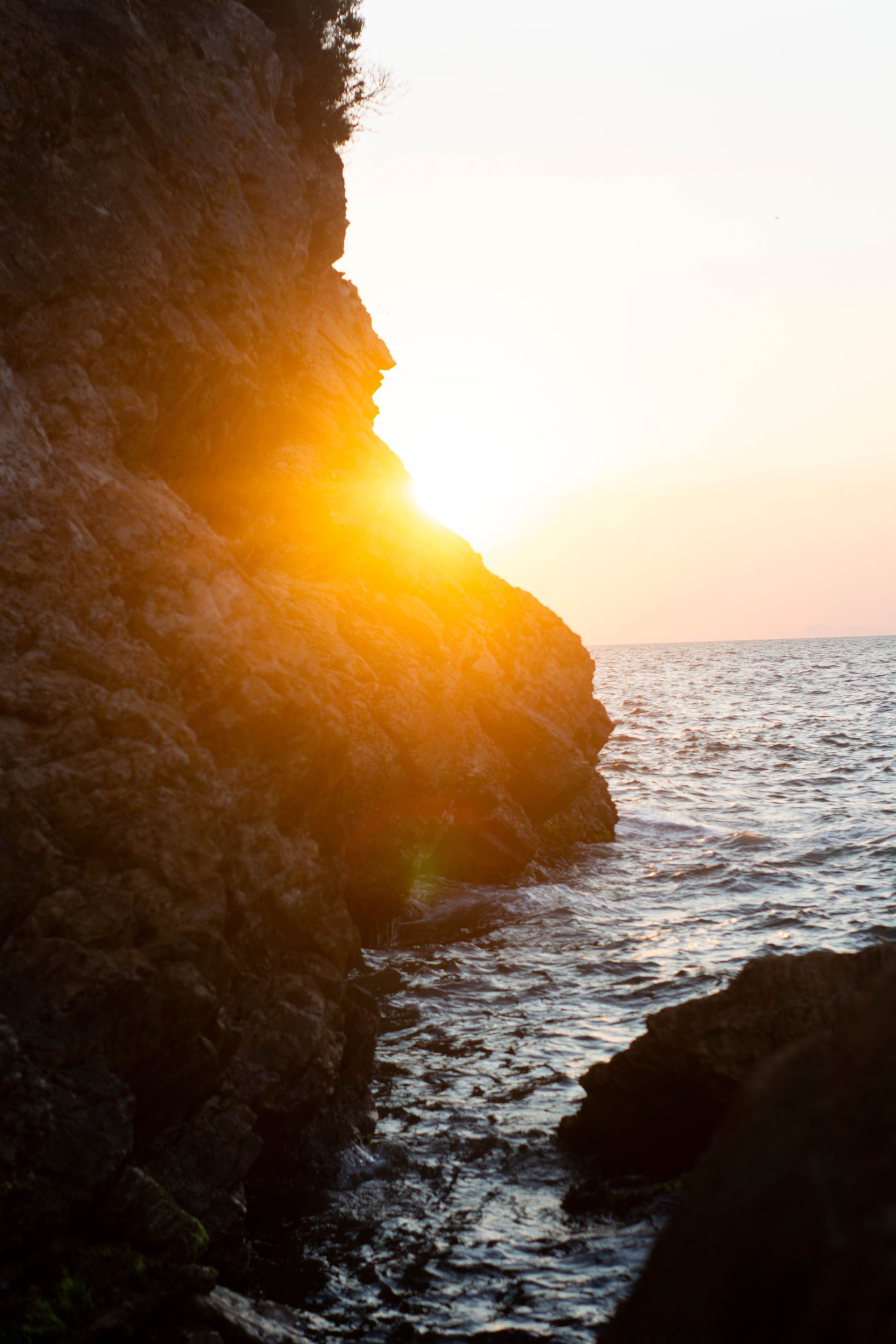 Sunlit ocean cliffs at last light, surf breaking far below