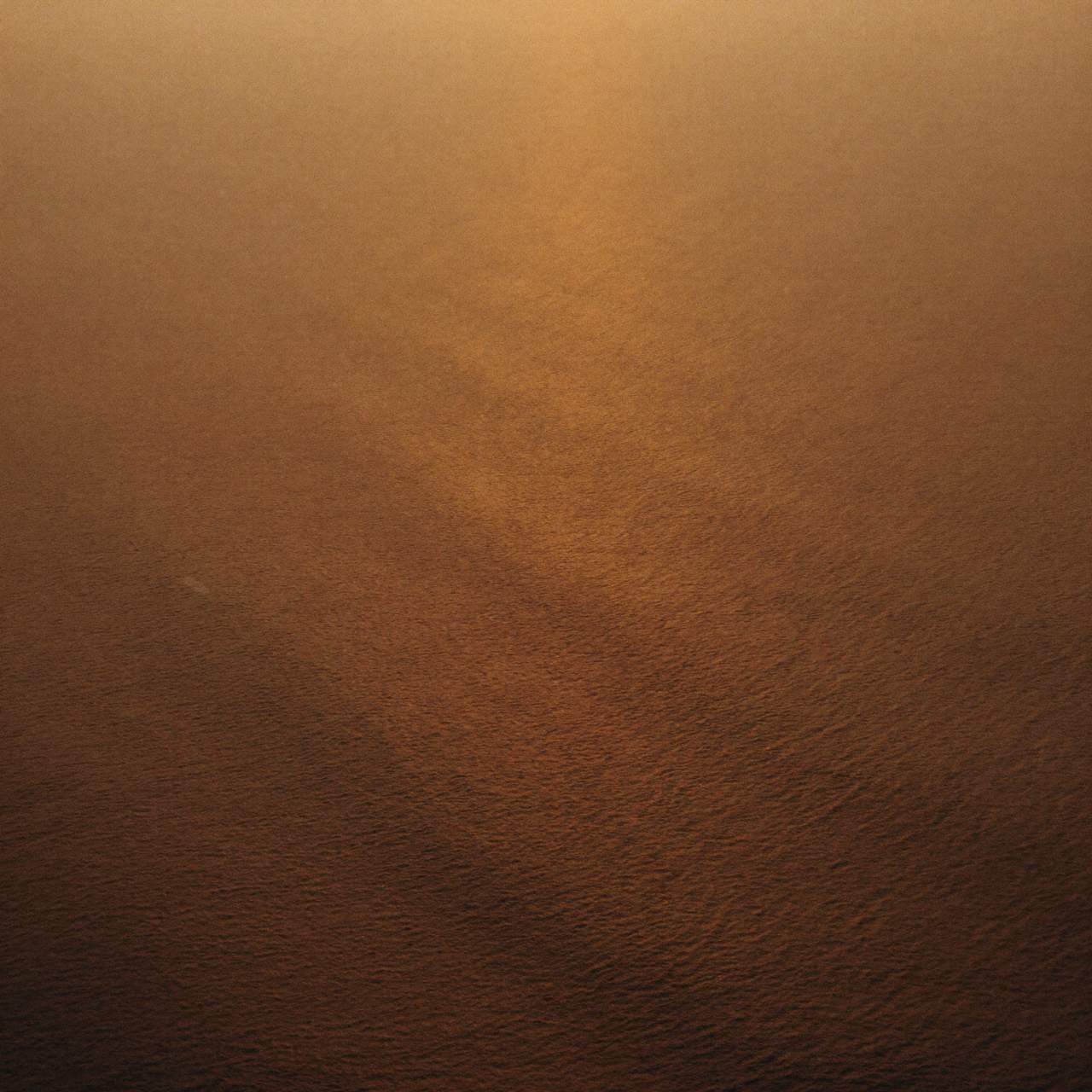 Golden water moving over textured sand at last light